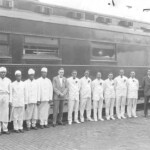 A Southern Railway dining car with full crew and two railroad officials pause in Ferguson on a trip South. Since this was the midpoint of the North South runs, the dining cars needed servicing just as much as the engines did. They would take on additional food, milk, ice and water, have their steam tables re-pressurized and their rest rooms cleaned. Occasionally a crew member would get on or off here, but that was rare. Usually, the dining crews worked all the way through from one end to the other.