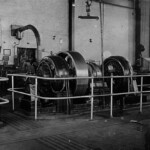 A wheeler (under the exhaust pipe) comes on duty while a coworker kneels over a pile of sheeting in the lower right corner. These machines, carefully railed off to prevent accidents, were used to grind, smooth, and "true" wheels for the big engines or occasionally a freight or passenger car or caboose. The wheels were too big and heavy for the men to move by hand. They were moved into place and picked up off the machines by specially adapted fork lifts. Although long gone from Ferguson, the same machines are still being used at rail shops in other states. The modern versions use computers, lasers and digital readouts to fine tune curvatures, but the basic principles remain the same.