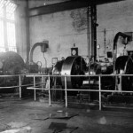 This is another view of the same scene as above (the exhaust pipe on the right is the same one seen in the previous photo). These jobs were extremely high paying but were very difficult and dangerous. After a decade of this work, a man was almost guaranteed to be at least partially deaf because as the grinders smoothed out the large heavy wheels they made a terrific screeching noise, and no one back then wore ear plugs. Frank Muse dismissed the skill involved. "Just think of a lathe with a long piece of wood you're making into a chair leg. Here the lathe is very short, the long cylinder is a narrow disc, and instead of wood we use iron. But the concept is the same."